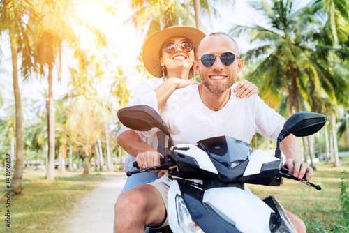 Сouple travelers riding motorbike scooter under palm trees. Traveling, vacation and transportation concept image