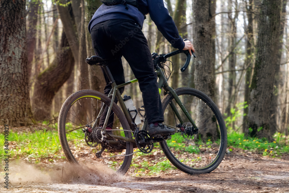 Cyclist on a gravel bike. A cyclist rides along a forest path drifting with the rear wheel and raising the pitch.