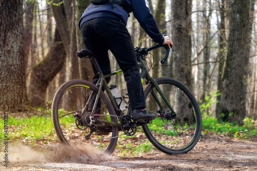 Cyclist on a gravel bike. A cyclist rides along a forest path drifting with the rear wheel and raising the pitch.