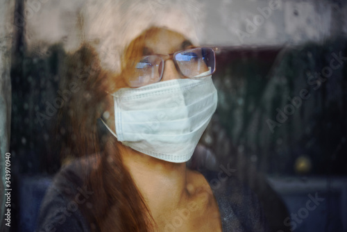 Woman looking through the wet window during stay home while COVID-19 photo