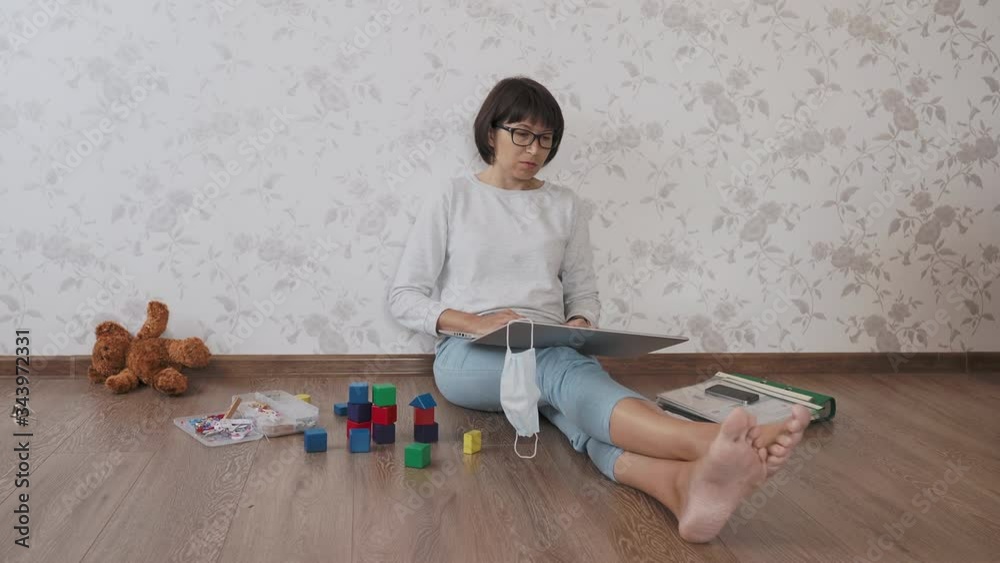 Mom and son sit at home quarantine because of coronavirus COVID19. Mother works remotely among with toys. Self isolation at home.