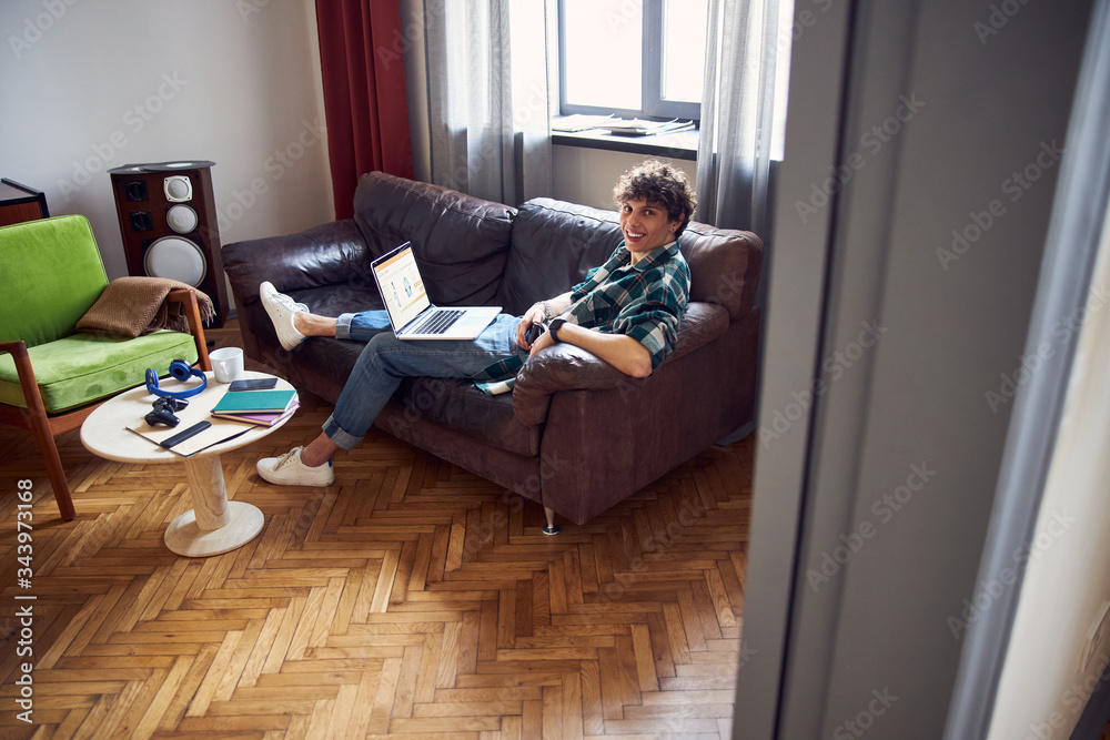 Cheerful young man using laptop at home