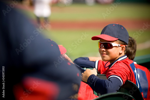 Boy wearing sunglasses and smirking in baseball uniform