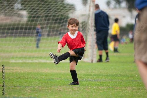 Young boy with big smile kicking an imaginary soccer ball photo