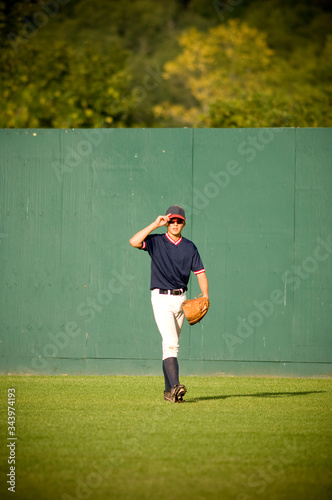 Young outfielder adjusting his sunglasses on baseball field