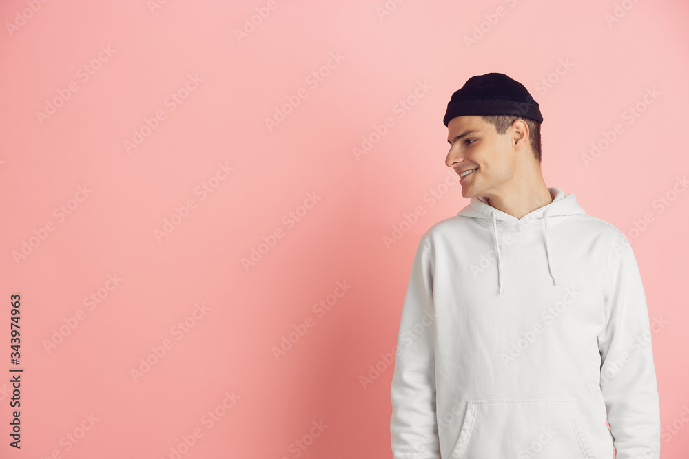 Looking at side. Caucasian young man's modern portrait isolated on pink studio background. Beautiful male model in white. Concept of human emotions, facial expression, sales, ad. Copyspace. Looking at side. Caucasian young man's modern portrait isolated on pink studio background. Beautiful male model in white. Concept of human emotions, facial expression, sales, ad. Copyspace.