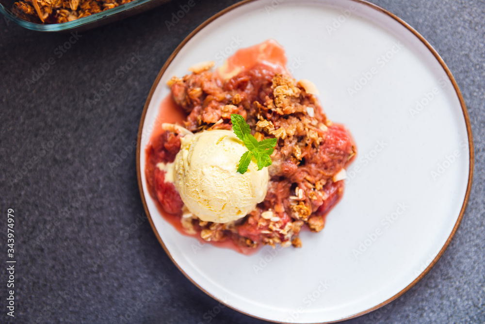 Home cooked Rhubarb and Strawberry crumble from oatmeal and nuts topping and with vanilla ice cream scoops