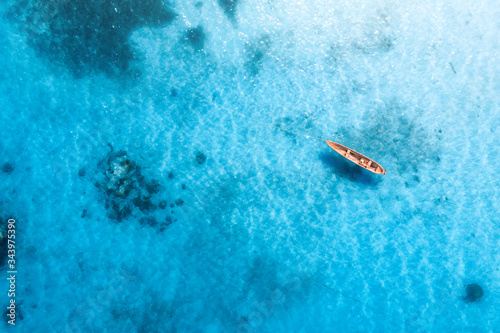 Aerial view of the fishing boat in transparent blue water at sunny day in summer. Top view from above of boat, sandy beach. Indian ocean in Zanzibar, Africa. Landscape with canoe and clear sea. Travel © den-belitsky