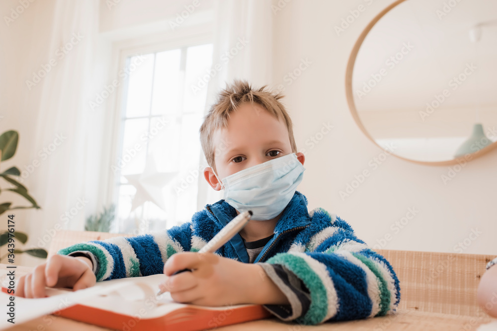 boy home schooling with a medical mask on to protect from a virus boy home schooling with a medical mask on to protect from a virus