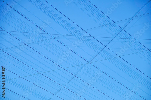 Black lines against a blue sky. the lines are power lines crisscrossing the photo.