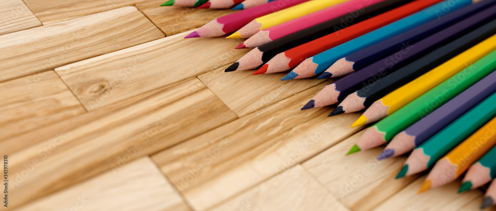 Colored pencil row on wooden background.