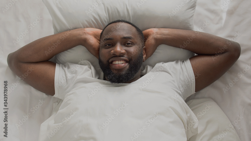 Young and successful man joyfully meeting new day morning in his bed, top view Young and successful man joyfully meeting new day morning in his bed, top view