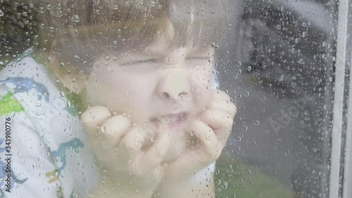 Boy looking out of window on a rainy day themes of sadness solitude emotions
