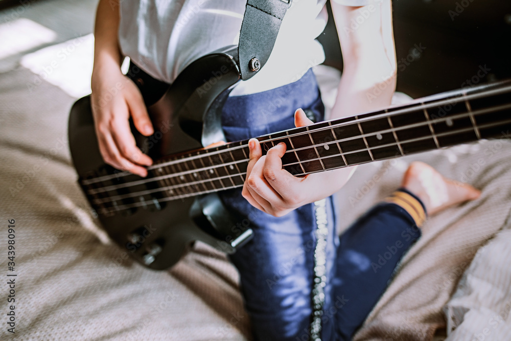 close up on the fingers of young girl playing bass guitar