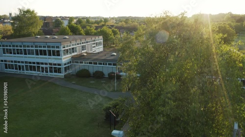 Aerial drone view taking off in front of a generic school building during a summer sunset