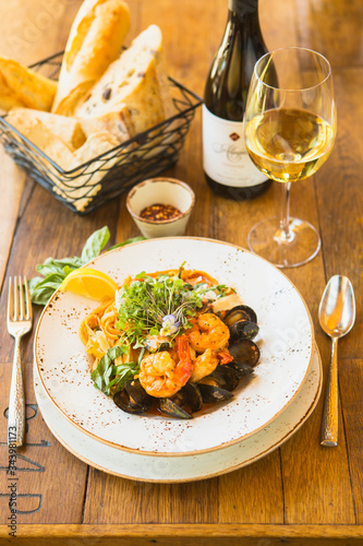 Canvas Print seafood fettuccine with sauteed white prawns, mussels and fish with a glass of c