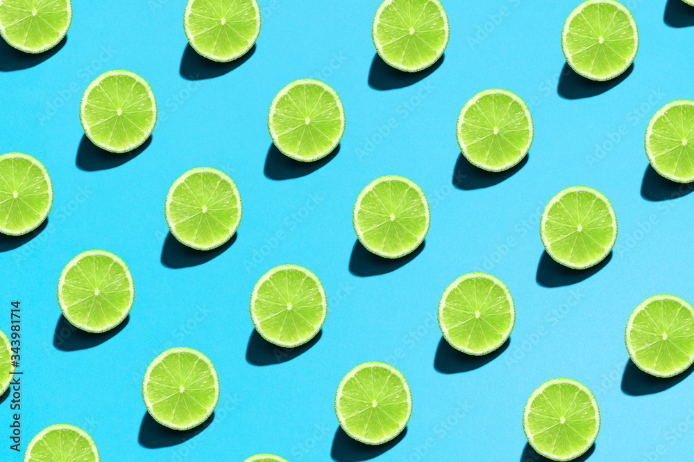 Lime pattern on bright light blue background. Minimal flat lay food texture. Summer abstract trendy fresh concept.