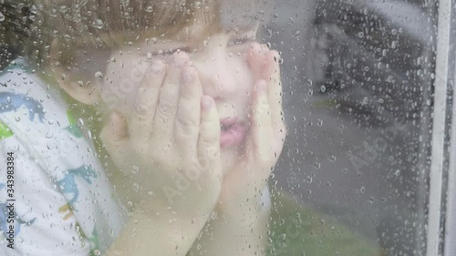 Boy looking out of window on a rainy day themes of sadness solitude emotions