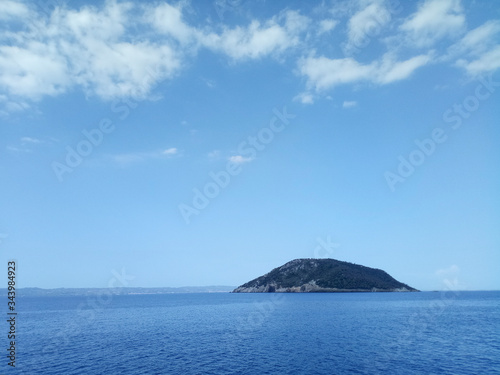 Small island in the middle off the sea ocean with bright blue sky and small clouds. Horizontal landscape. © Studio f20