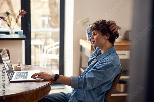 Handsome smiling guy sitting at the table and using laptop