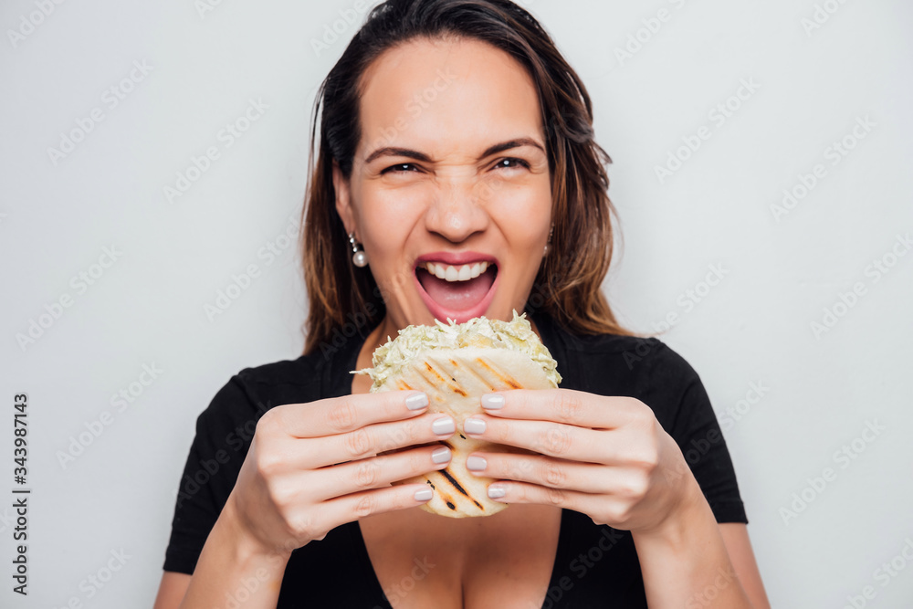 Latin girl holds an arepa in her hands ready to eat it, the arepa is a pepeada queen, typical Venezuelan arepa Latin girl holds an arepa in her hands ready to eat it, the arepa is a pepeada queen, typical Venezuelan arepa