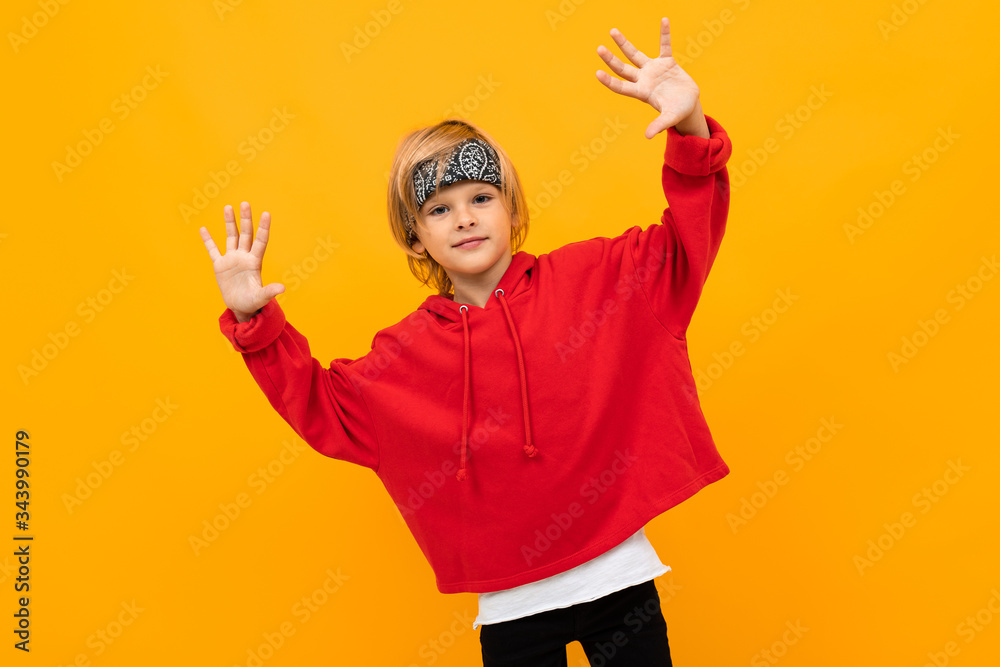 Stylish young boy in red sweatshirt and white t-shirt puts hands on his chest Stylish young boy in red sweatshirt and white t-shirt puts hands on his chest