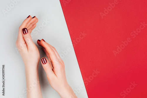 Red beautiful manicure on red and grey stylish background with copyspace. Flat lay style. photo