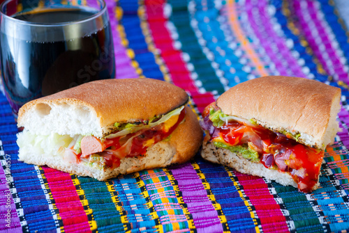 Tasty bread prepared with fathoms, with salchica, avocado, vegetables and homemade sauces on a typical Guatemalan mat called Shuco. photo