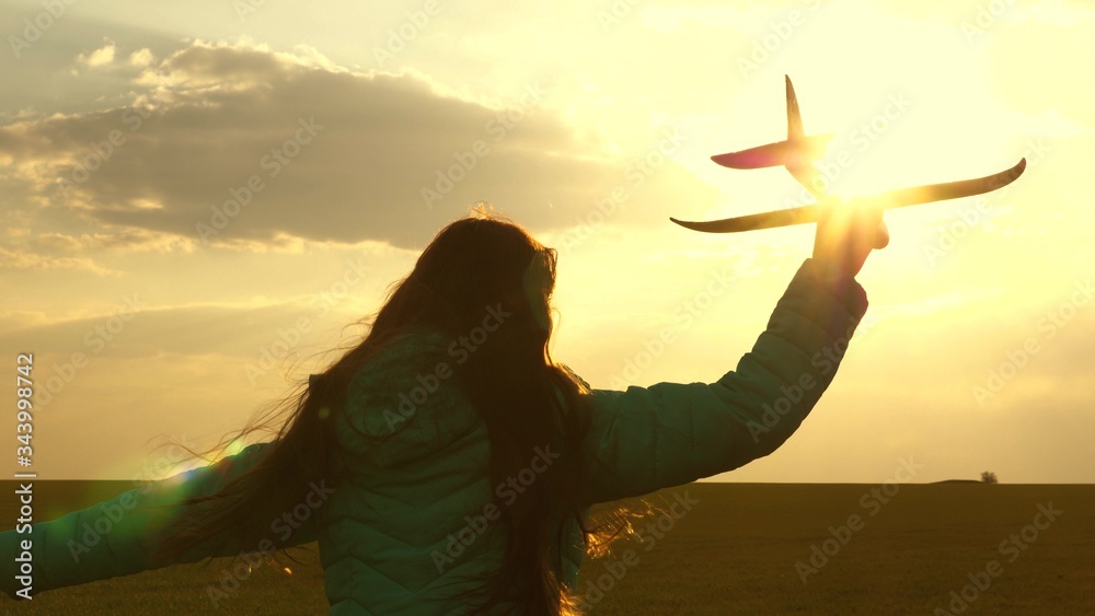 Happy girl runs with toy airplane on a field in the sunset light. children play toy airplane. teenager dreams of flying and becoming a pilot. girl wants to become a pilot and astronaut. Slow motion