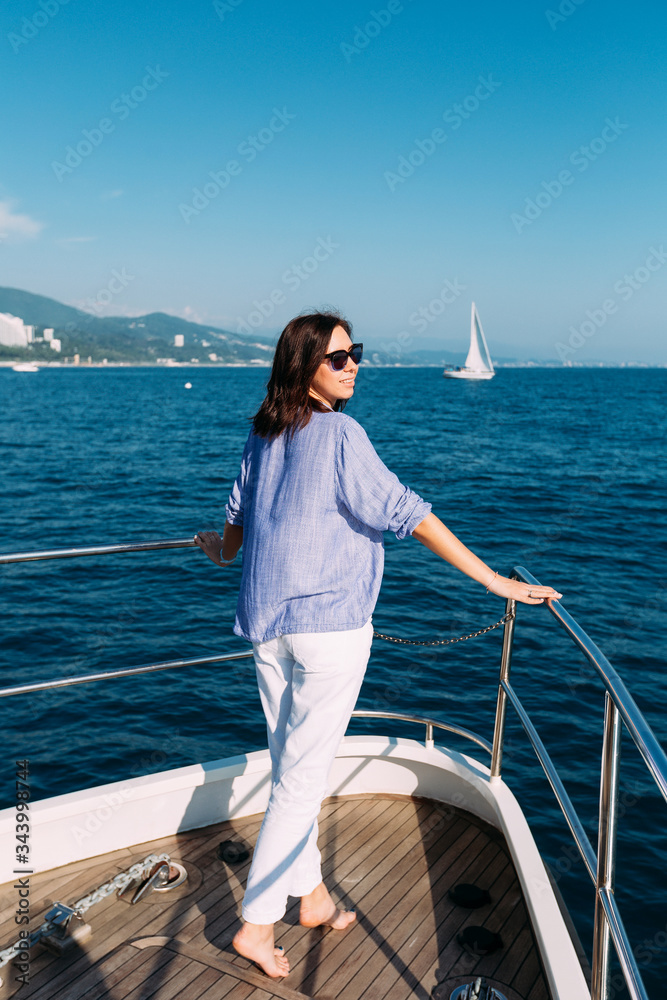 The girl stands with her back to the ship and looks out to sea