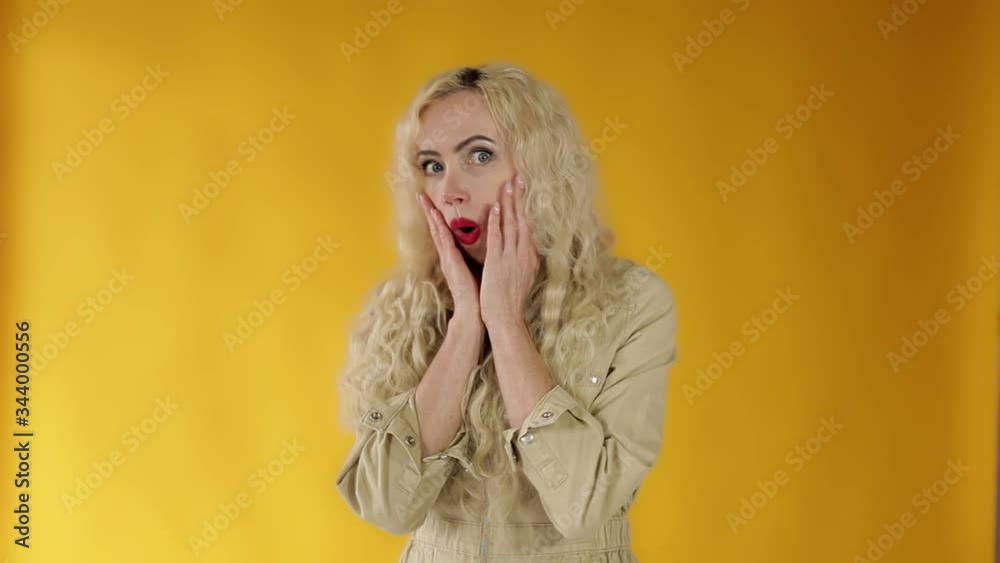 Embarrassed European woman blonde frowning rounds her eyes, holding her hand on Embarrassed European woman blonde frowning rounds her eyes, holding her hand on