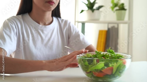 The unhappy dieting Asian girl has a boring expression, She doesn't like to eat vegetables, Health and vegetarian concepts.