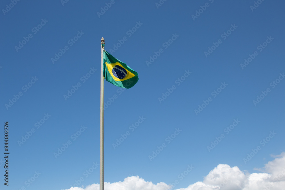 Bandeira do Brasil desgastada com o tempo no céu azul Bandeira do Brasil desgastada com o tempo no céu azul