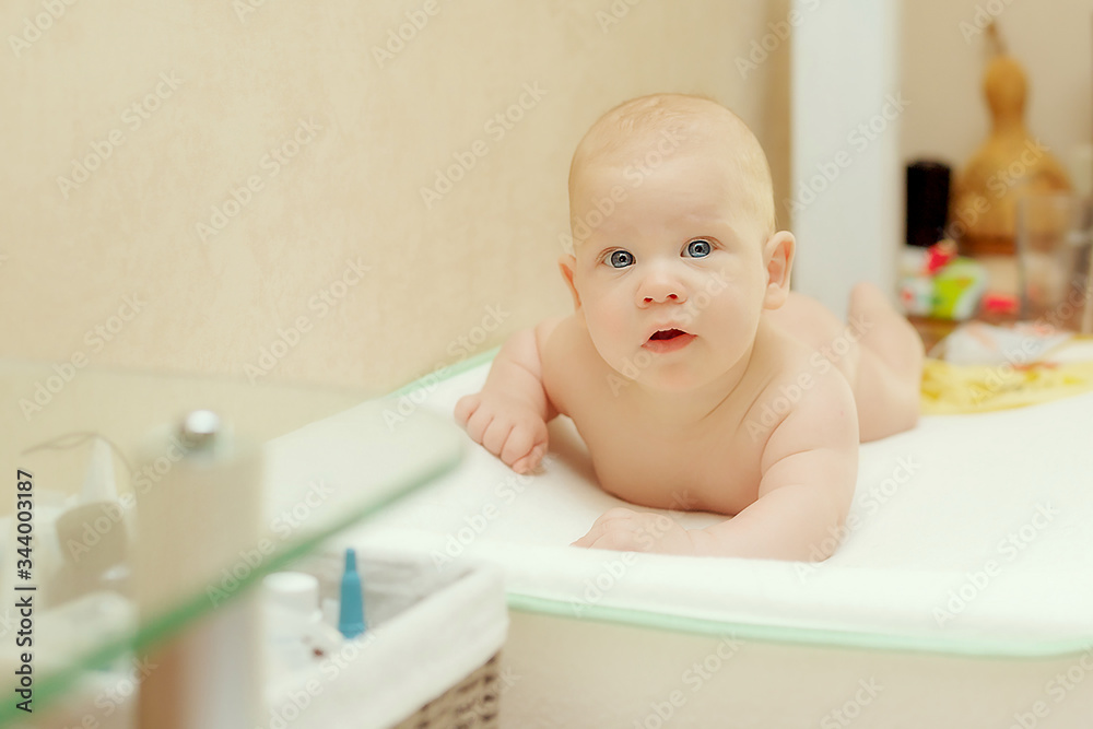 Cute infant baby boy on a changing table at home curious Cute infant baby boy on a changing table at home curious