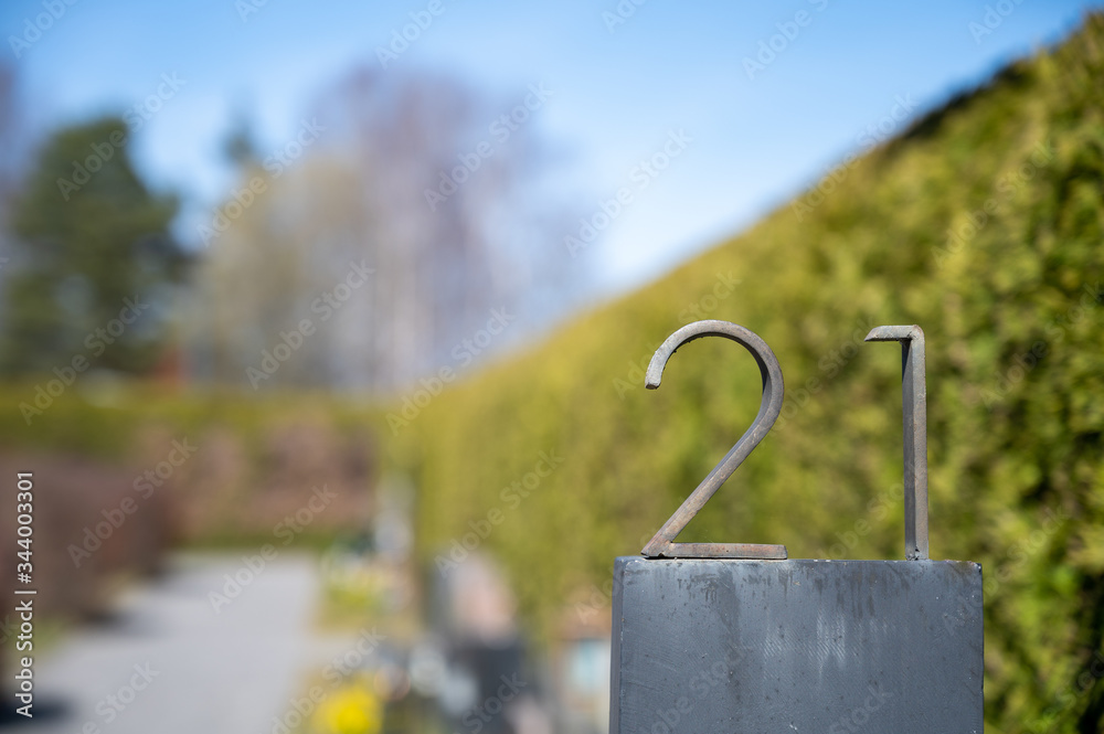 Closeup of metal number 21 sign agains green bush background. Closeup of metal number 21 sign agains green bush background.