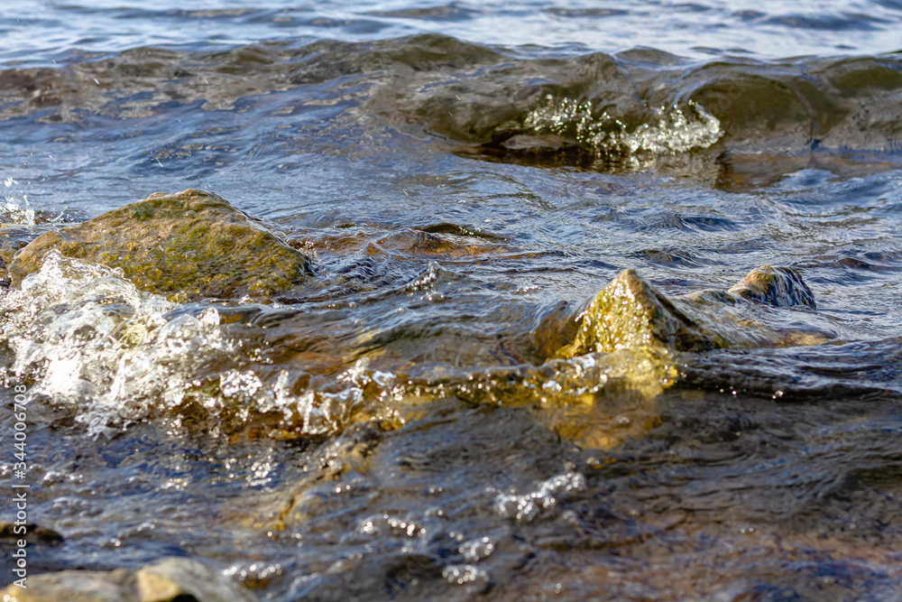 Rocky riverbank. Waves rise against rocks.