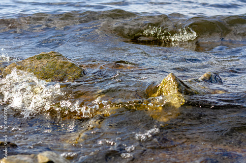 Rocky riverbank. Waves rise against rocks.