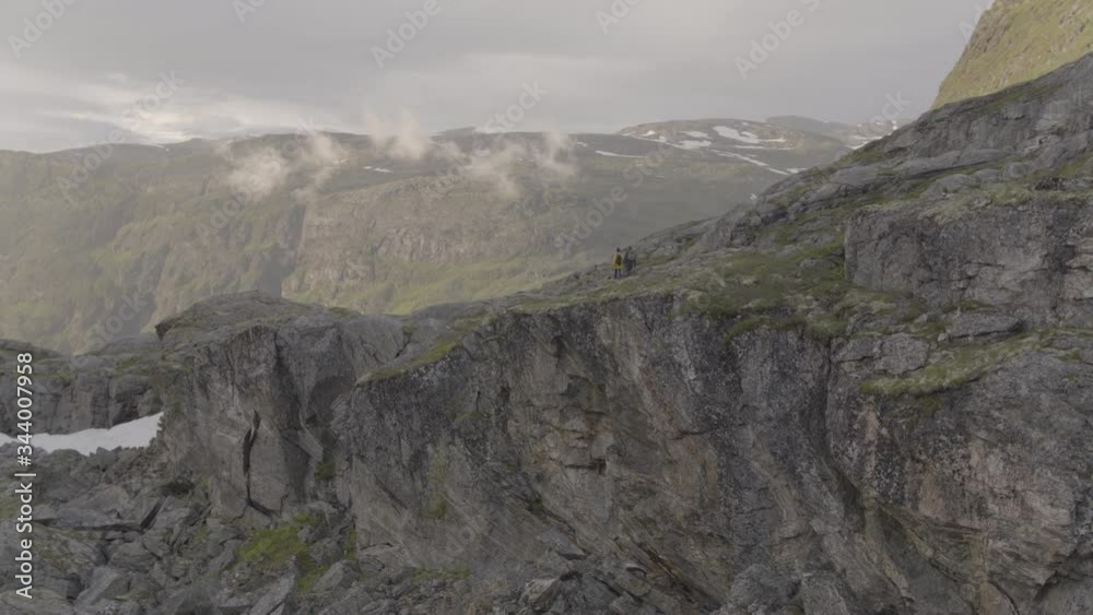 aerial drone view of hikers approaching a waterfall on top of a norwegian fjord aerial drone view of hikers approaching a waterfall on top of a norwegian fjord