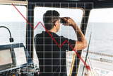 Concept of falling market in marine industry with downward graphics. Officer during navigational watch looking through binoculars.