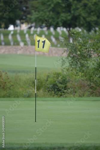 a yellow golf hole flag blows in the wind on a golf course on a sunny summer afternoon 