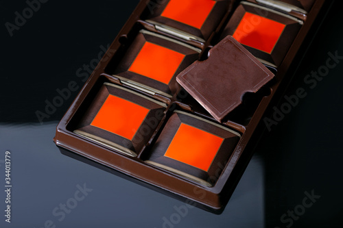 Chocolate bar in container on black background. Premium chocolate ads.