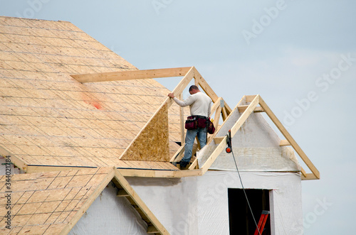 Photography construction worker on a roof frames in a dormer on a new home construction