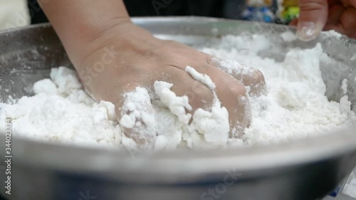 Asian young woman is making Thai dumplings dessert or Bualoy sweets. Close-up of the process of mixing flour with coconut milk and kneading the dough to make Bualoy balls. photo