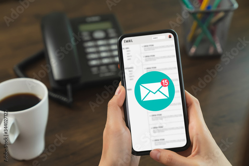 Hand holding smartphone and show email screen on application mobile in the office.