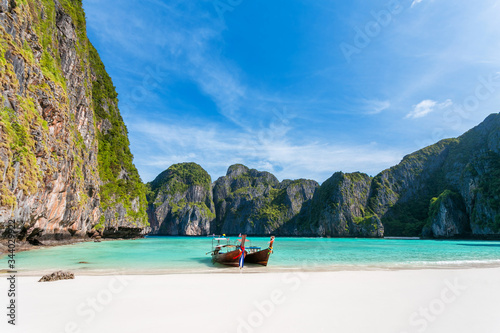 Tropical beach background. Panoramic views of Maya Bay with a longtail boat parked. overlooking white sand beach, clear water and beautiful sky. Phi Phi Leh island Krabi Province, Thailand.