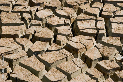 Parched ground with large mudcracks in the dried mud. Drought induced dehydrated land. 