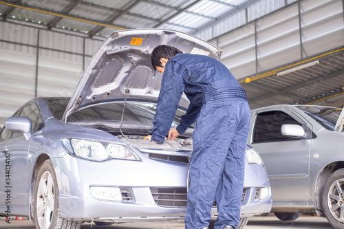 The mechanic is checking the car's engine in the car repair center. Annual vehicle inspection before registration or tax payment.