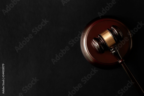 Top view of wooden judge gavel and sounding block on black leather top table.