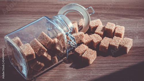 Brown cane refined sugar in a jar on a wooden background.