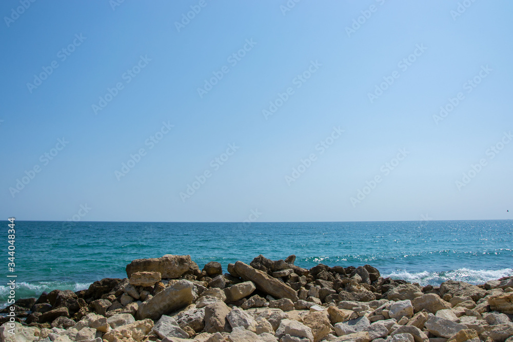 Beautiful wild beach landscape, sunny day, water waves hitting the cliffs, nature summertime scene